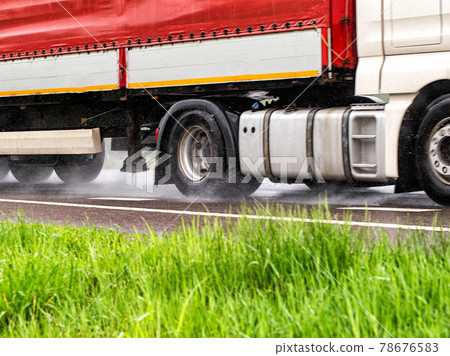 Truck tires in wet weather on wet asphalt. Wet weather road safety concept. Braking distance and aquaplaning characteristics on the road. Close-up Truck tires in wet weather on wet asphalt. Wet weather road safety concept. Braking distance and aquaplaning characteristics on the road. Close-up 78676583