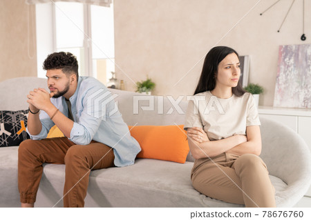 Upset husband and wife sitting on couch Upset husband and wife sitting on couch 78676760