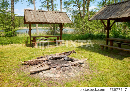 Bonfire and picnic area in a forest by a lake. Bonfire and picnic area in a forest by a lake. 78677547