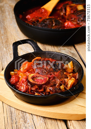 Closeup view of cast iron skillet with ossobuco Closeup view of cast iron skillet with ossobuco 78678315