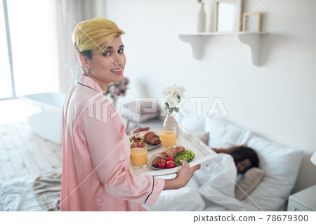 Woman with breakfast tray for dark skinned sleeping girlfriend Woman with breakfast tray for dark skinned sleeping girlfriend 78679300