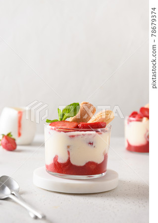 Layered dessert in glass jars with cookie savoyardi, mascarpone and whipped cream decorated strawberries 78679374