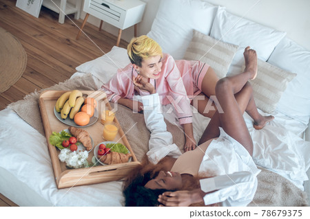 Two girlfriends in playful mood relaxing on bed Two girlfriends in playful mood relaxing on bed 78679375