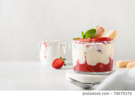 Layered dessert in glass jars with cookie savoyardi, mascarpone and whipped cream decorated strawberries Layered dessert in glass jars with cookie savoyardi, mascarpone and whipped cream decorated strawberries 78679378