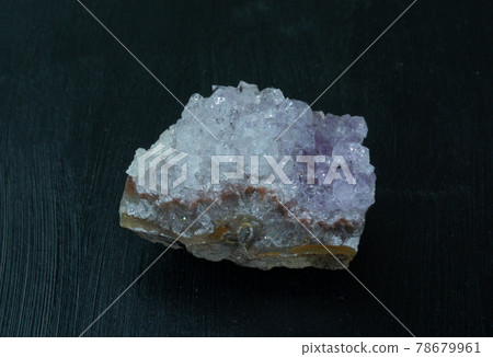 Amethyst violet variety of quartz from Brazil. Natural mineral stone on black background. Mineralogy, geology, magic of stones, semi-precious stones and samples of minerals. Close-up macro photo. 78679961