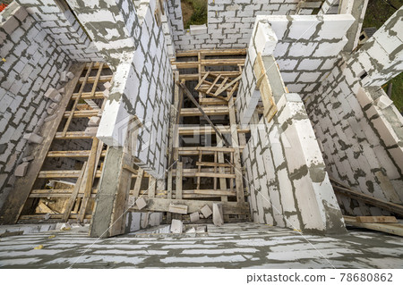 View from above of future multi stored cottage energy saving walls of large white hollow foam insulation blocks and temporary wooden scaffolding frame. Construction masonry, modern technology concept. 78680862