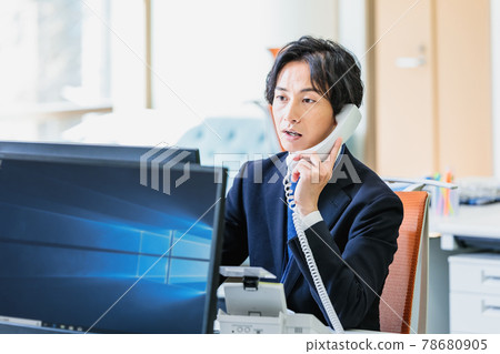 A businessman who uses a personal computer while receiving a call A businessman who uses a personal computer while receiving a call 78680905