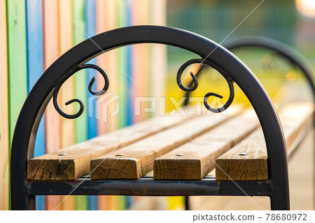 Closeup of wooden park bench with metal handgrip outdoors. Closeup of wooden park bench with metal handgrip outdoors. 78680972
