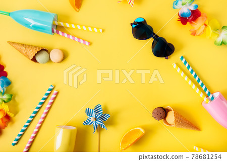 Top view flat lay of bright cocktail glasses with straws, Hawaii flower necklaces, sunglasses, waffle cones, macaroon cakes, orange slices on the yellow background. Love Summer party mood. Copy space. 78681254