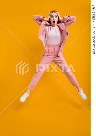 Surprised wondered redhead business lady jumping omg expression, isolated on yellow Surprised wondered redhead business lady jumping omg expression, isolated on yellow 78681464