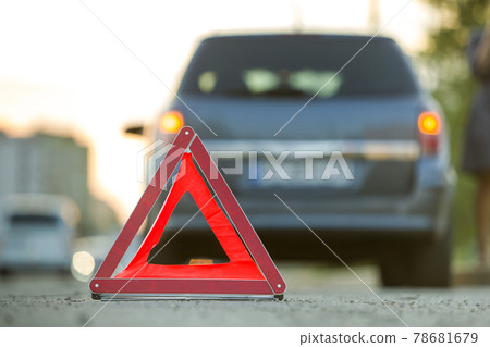 Red emergency triangle stop sign and broken car on a city street. Red emergency triangle stop sign and broken car on a city street. 78681679