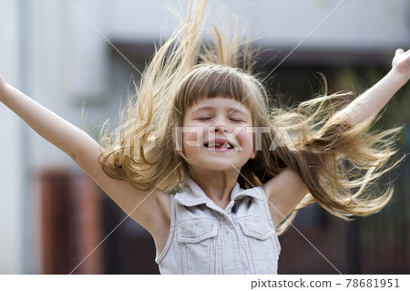 Pretty little preschool girl in sleeveless white dress with beautiful long blond hair blown by wind, funny toothless smile and spread arms on blurred background. Innocent happy childhood concept. Pretty little preschool girl in sleeveless white dress with beautiful long blond hair blown by wind, funny toothless smile and spread arms on blurred background. Innocent happy childhood concept. 78681951
