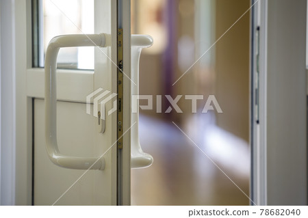 White plastic door detail with metal lock, handle and transparent glass on blurred interior background. Installation and design concept. 78682040