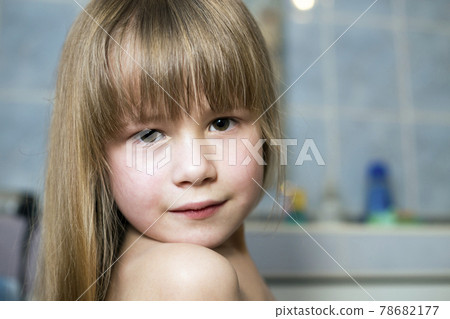 Pretty girl face portrait, smiling child with beautiful eyes and long wet fair hair on blurred background of bathroom. 78682177