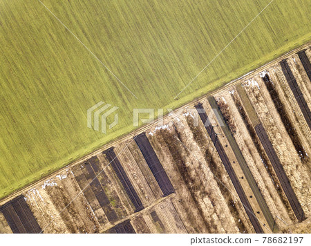 Agricultural landscape from air. Straight narrow ground road between sunny green, dry and brown plowed fields. Agricultural landscape from air. Straight narrow ground road between sunny green, dry and brown plowed fields. 78682197