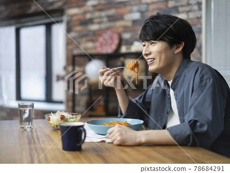 A young man eating pasta A young man eating pasta 78684291