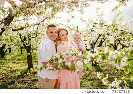 mom, dad and daughter in spring flowering garden. cleft lip in infants. mom, dad and daughter in spring flowering garden. cleft lip in infants. 78687538