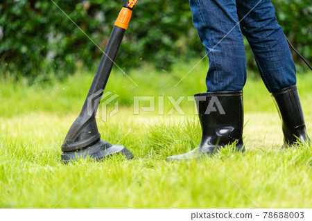 worker using a string lawn trimmer mower cutting grass worker using a string lawn trimmer mower cutting grass 78688003