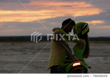 Couple embracing near motorbike on beach at sunset Couple embracing near motorbike on beach at sunset 78689849