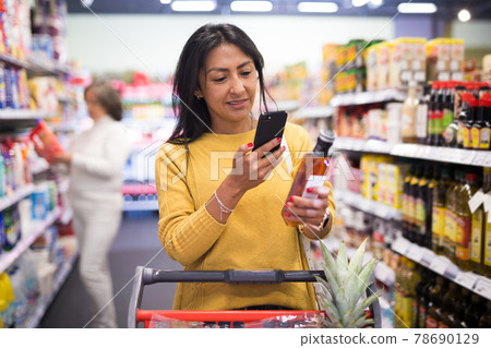 Shopper using smartphone scans qr code on label in supermarket Shopper using smartphone scans qr code on label in supermarket 78690129