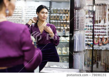 Woman trying on necklace in bijouterie store Woman trying on necklace in bijouterie store 78690131