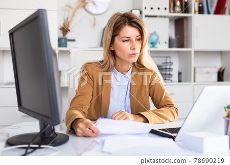 Woman working with papers and laptop 78690219