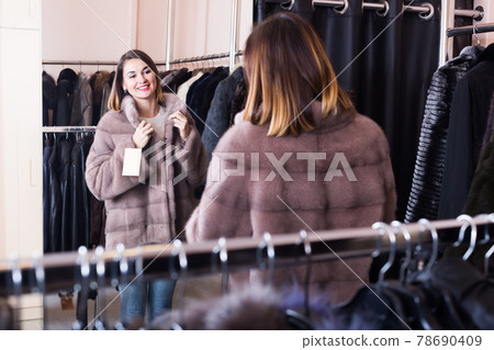 Young girl deciding on the choice of fur coat Young girl deciding on the choice of fur coat 78690409