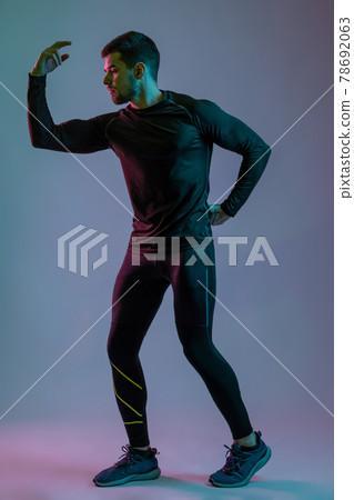 Guy in black sportswear showing his athletic physique 78692063