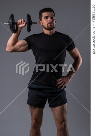 Sporty young man doing dumbbell one arm shoulder press Sporty young man doing dumbbell one arm shoulder press 78692116