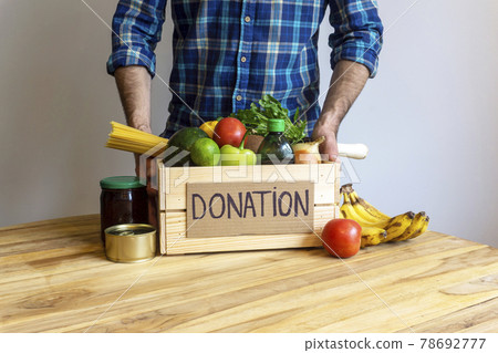 Food donation concept. A man holding a donation box with vegetables, fruits and other food for donation 78692777