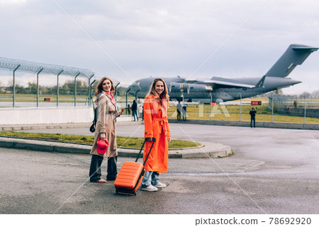 Two happy girls walking near airport, with luggage. Air travel, summer holiday Two happy girls walking near airport, with luggage. Air travel, summer holiday 78692920
