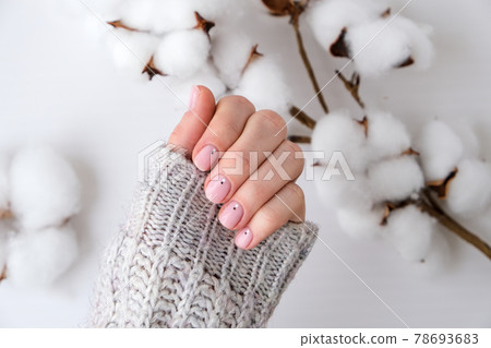 Woman hands with beautiful nude manicure holding delicate white cotton flower. Female Manicure, natural look. Nails care. Self care. 78693683