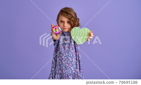 Teen age Girl in blue summer flower print dress holding pop it antistress toy on lavender background, isolate.  78695186