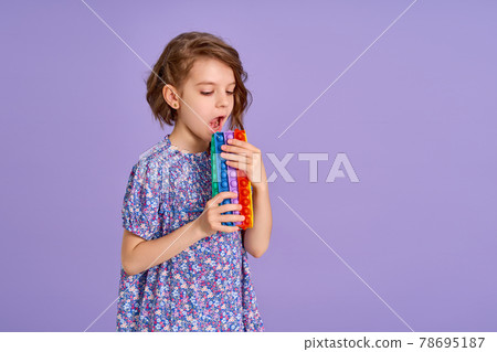 Teen age Girl in blue summer flower print dress holding pop it antistress toy on lavender background, isolate.  78695187