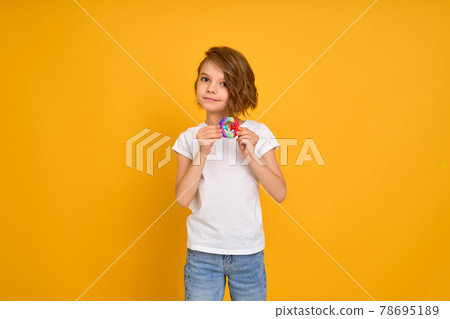 little girl holding pop it antistress toy on yellow background 78695189