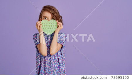 Teen age Girl in blue summer flower print dress holding pop it antistress toy on lavender background, isolate.  78695190
