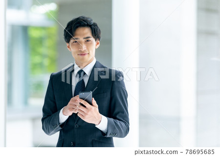 穿著西裝的商人在辦公室拿著智慧型手機 78695685