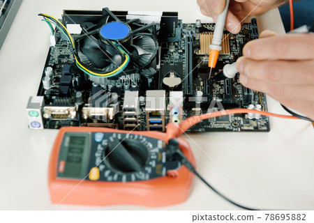 A technician checks the serviceability of the computer motherboard. 78695882