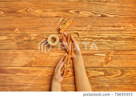 Cinnamon sticks in hands on a wooden background. 78695955