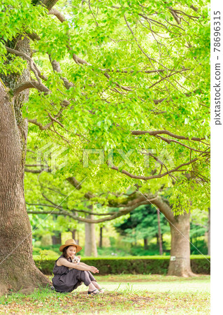 A young woman taking a walk with a small dog Kashiwanoha Park 78696315