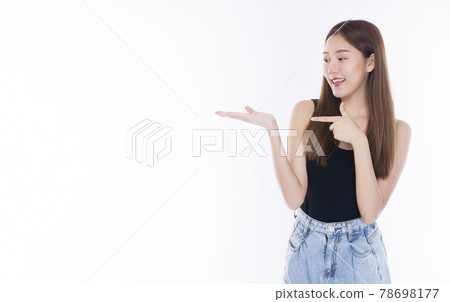 Cheerful young woman holding her hand and pointing to empty copy space while standing over isolated Cheerful young woman holding her hand and pointing to empty copy space while standing over isolated 78698177