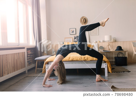 Meditating woman wearing a medical face mask to protect from corona virus, yoga position on mat home 78698480