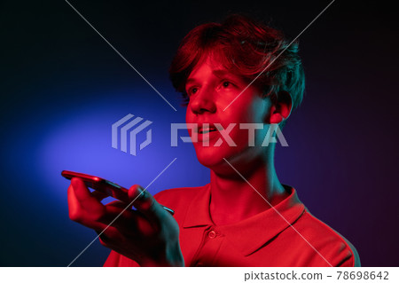 Recording voice message. man's modern portrait on gradient orange studio background in neon. Recording voice message. man's modern portrait on gradient orange studio background in neon. 78698642