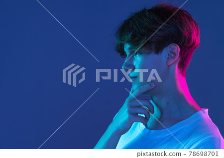 Caucasian young man's portrait on dark studio background in neon. Concept of human emotions, facial expression. Caucasian young man's portrait on dark studio background in neon. Concept of human emotions, facial expression. 78698701