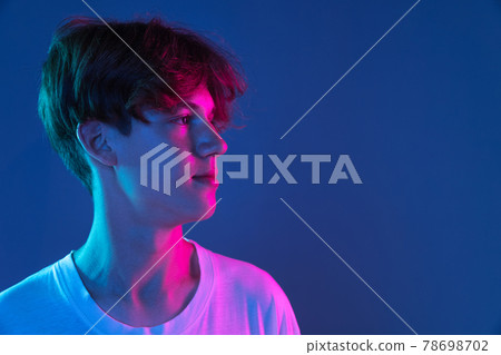 Caucasian young man's portrait on dark studio background in neon. Concept of human emotions, facial expression. Caucasian young man's portrait on dark studio background in neon. Concept of human emotions, facial expression. 78698702