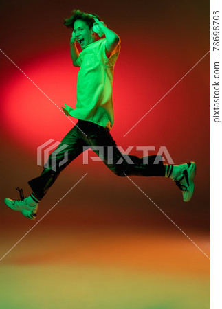 Caucasian young man in headphones isolated on blue studio background in neon. Concept of human emotions, facial expression. Caucasian young man in headphones isolated on blue studio background in neon. Concept of human emotions, facial expression. 78698703