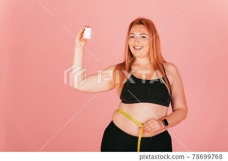 Cheerful plus size woman wearing sporty outfit measuring her waist 78699768