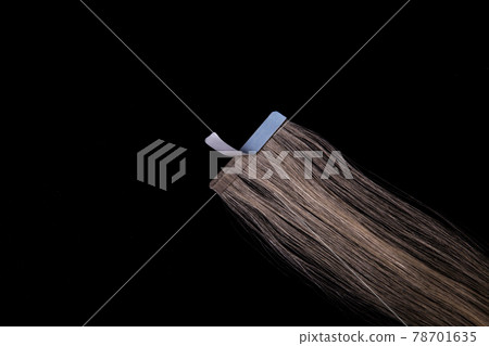 Fake blonde hair on sticky tape on black isolated background Fake blonde hair on sticky tape on black isolated background 78701635