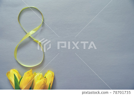Five yellow tulips on a grey background with the number eight made of ribbon 78701735