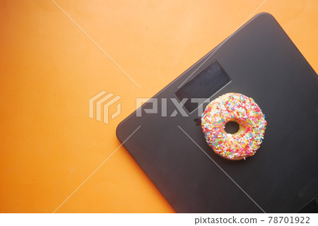 sweet donuts on weight scale on orange background  78701922